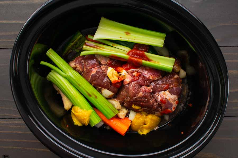 Pork, marinade, and broth seasonings in a 6-quart slow cooker