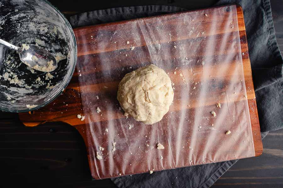 Ball of pie crust dough on plastic wrap