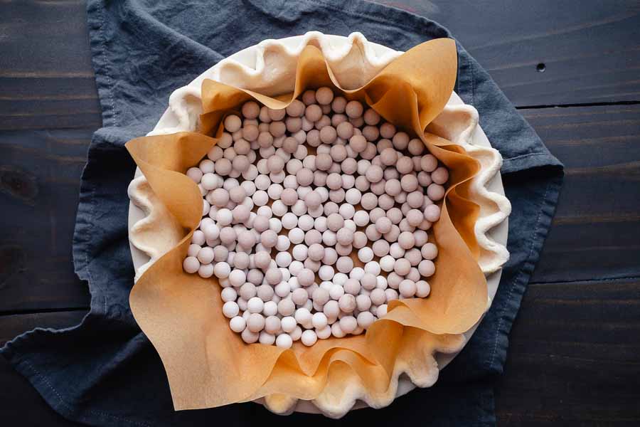 Pie weights in an uncooked pie crust lined with parchment paper