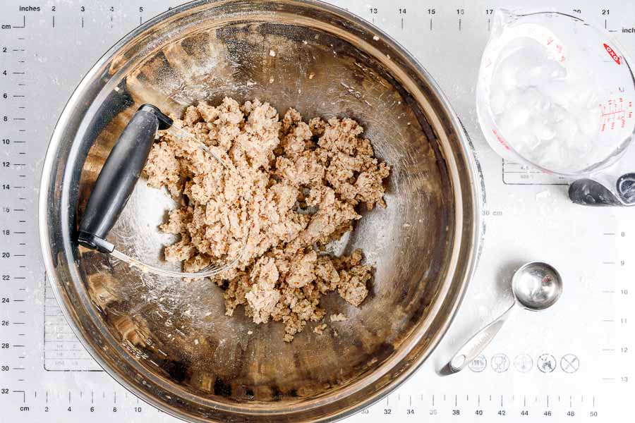 Pecan pie crust dough in a mixing bowl with a pastry cutter